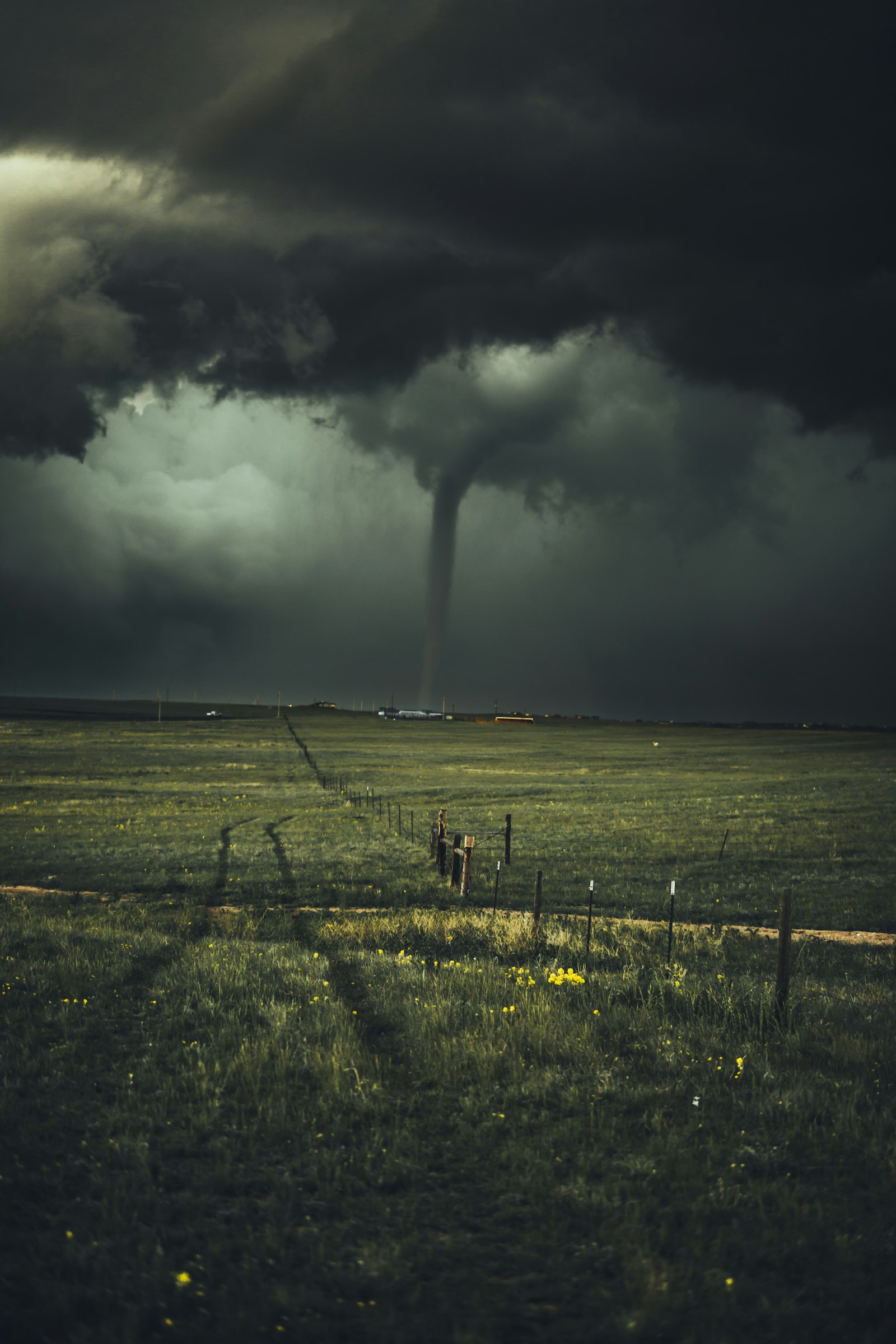 Storm funnel cloud descending over open fields